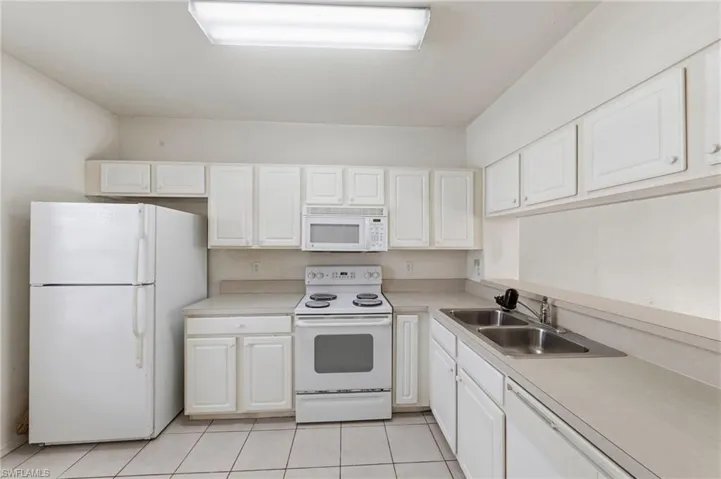Kitchen with white appliances, white cabinetry, light countertops, and light tile patterned floors