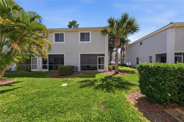 Rear view of property featuring stucco siding, a sunroom, and a yard