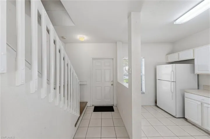 Kitchen with freestanding refrigerator, white cabinets, light tile patterned floors, and light countertops