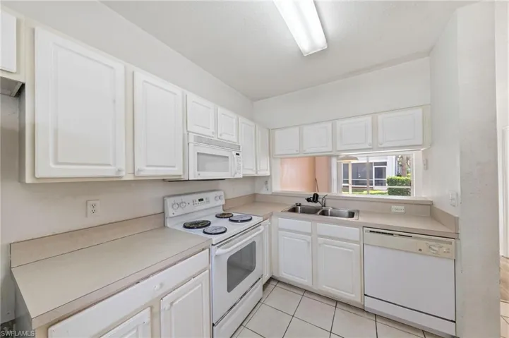 Kitchen with white appliances, white cabinets, light countertops, and light tile patterned floors
