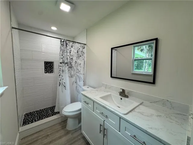 Full bath with vanity, a stall shower, and light wood-type flooring