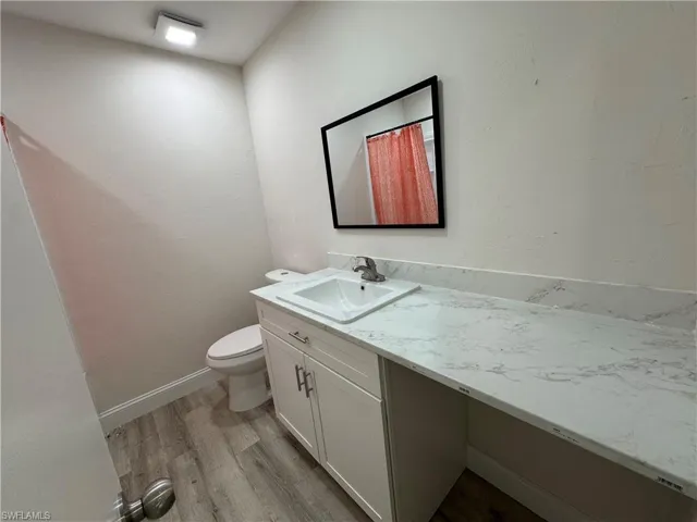 Full bath with light wood-style floors, vanity, and a textured wall