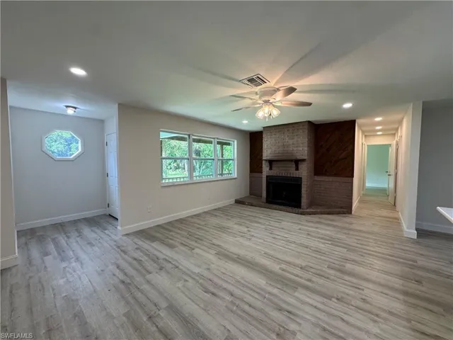 Unfurnished living room featuring ceiling fan, light wood finished floors, recessed lighting, and a brick fireplace