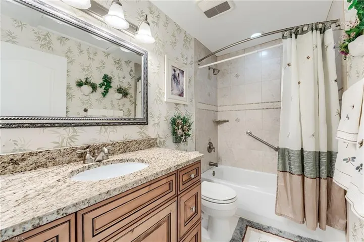 Full bath with shower / bath combination with curtain, visible vents, toilet, and wallpapered walls