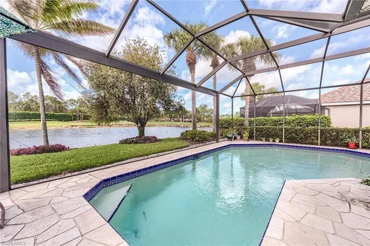 Outdoor pool featuring a patio, glass enclosure, and a water view