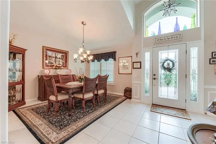 Entrance foyer featuring a notable chandelier, light tile patterned flooring, and lofted ceiling
