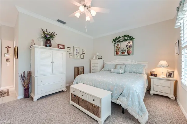 Bedroom with light carpet, visible vents, baseboards, and ornamental molding