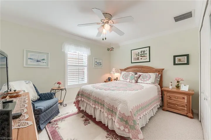 Bedroom with crown molding, ceiling fan, visible vents, light carpet, and baseboards