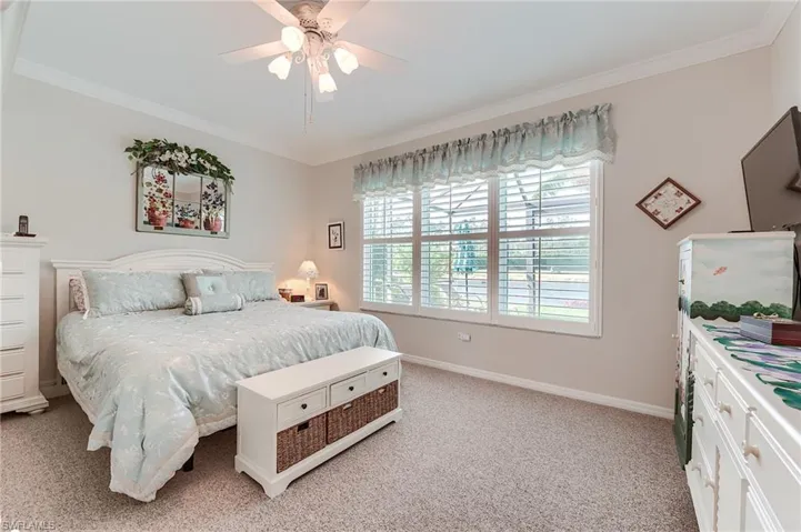 Bedroom with crown molding, baseboards, a ceiling fan, and light colored carpet