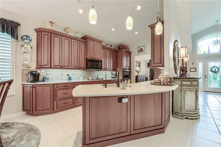 Kitchen with tasteful backsplash, light tile patterned flooring, a sink, and light stone countertops