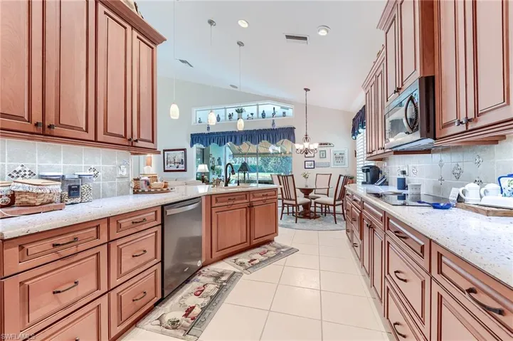 Kitchen with visible vents, appliances with stainless steel finishes, a chandelier, light stone countertops, and light tile patterned flooring