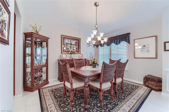 Dining room featuring light tile patterned floors, baseboards, a chandelier, and lofted ceiling