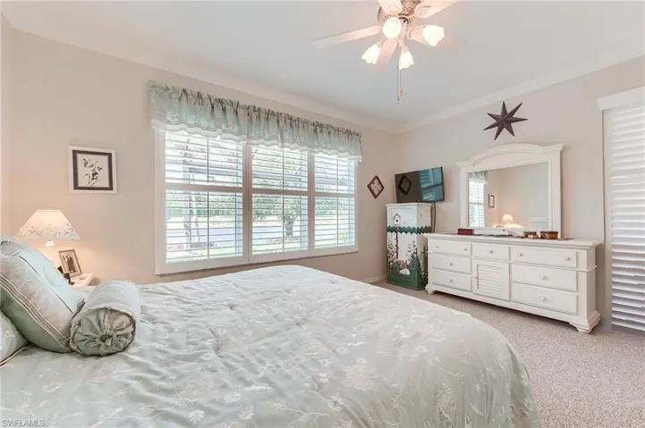 Bedroom with a ceiling fan, carpet flooring, and ornamental molding