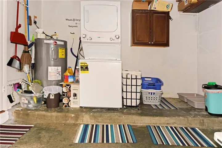 Laundry area with stacked washer / drying machine, concrete floors, and electric water heater