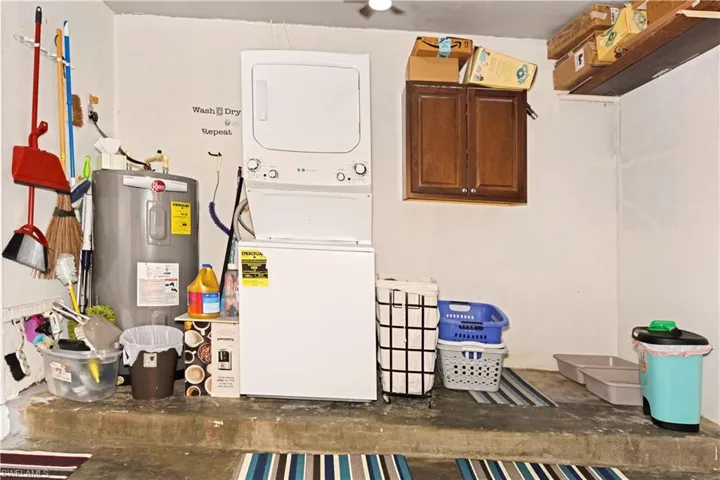 Laundry room featuring stacked washer and clothes dryer, electric water heater, and unfinished concrete floors