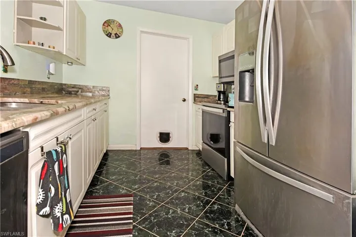 Kitchen featuring stainless steel appliances, light stone counters, white cabinets, and open shelves