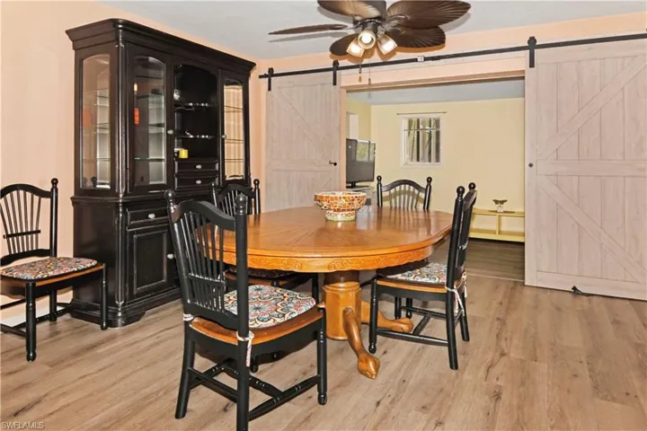 Dining room featuring a barn door, light wood-style floors, and a ceiling fan