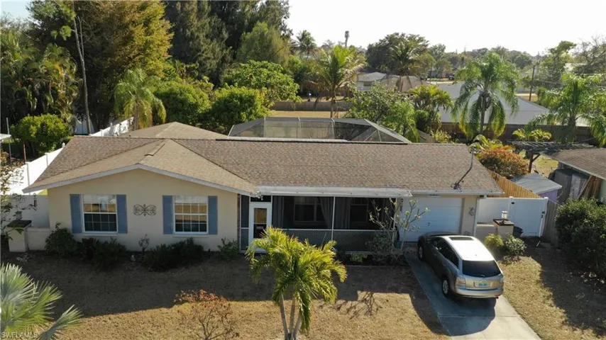 View of front of property featuring a shingled roof, a sunroom, stucco siding, an attached garage, and driveway