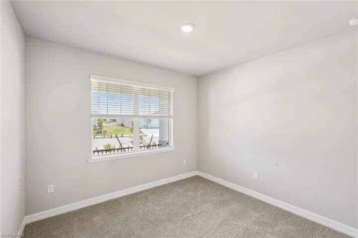 Carpeted spare room with baseboards and a smoke detector