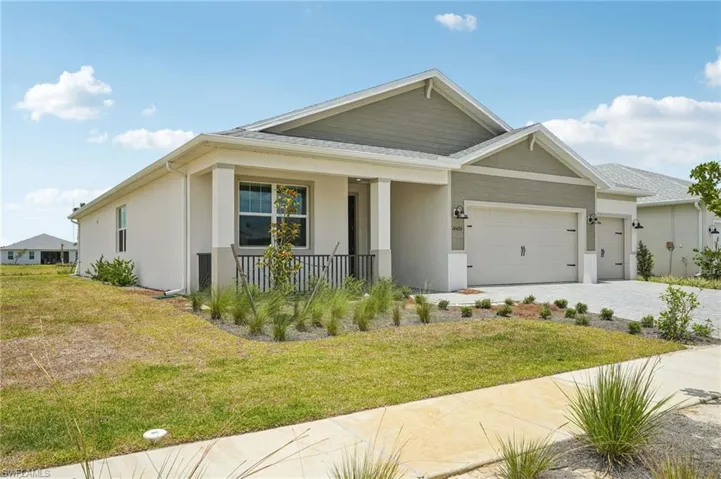 View of front of property with a porch, an attached garage, stucco siding, a front yard, and driveway