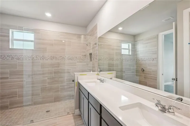 Bathroom with double vanity, a walk in shower, and recessed lighting