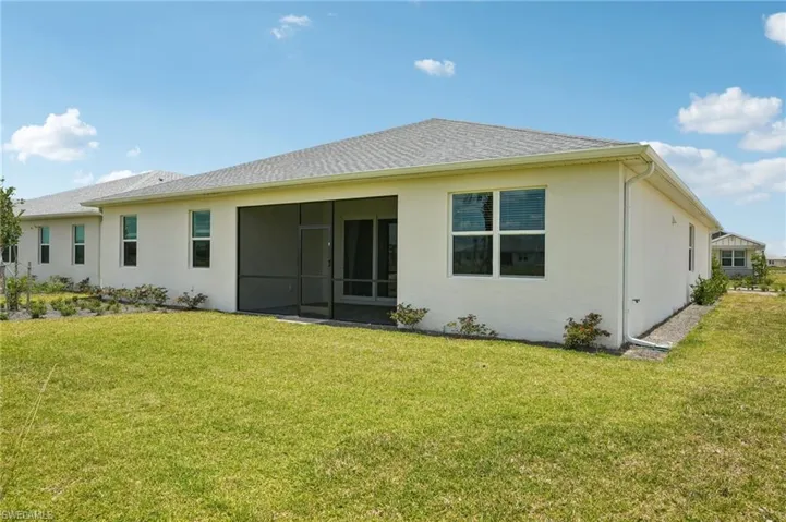 Rear view of house featuring a lawn, stucco siding, and a sunroom