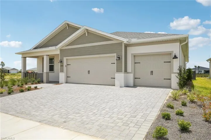 View of front facade featuring decorative driveway, an attached garage, and stucco siding