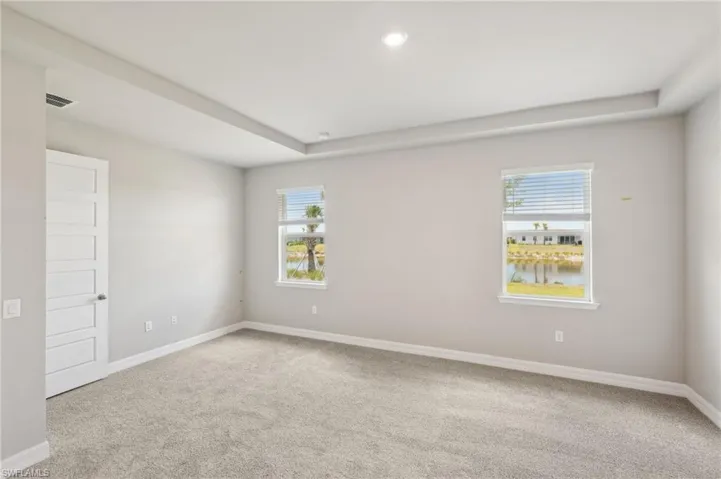 Carpeted spare room featuring baseboards, a raised ceiling, and recessed lighting