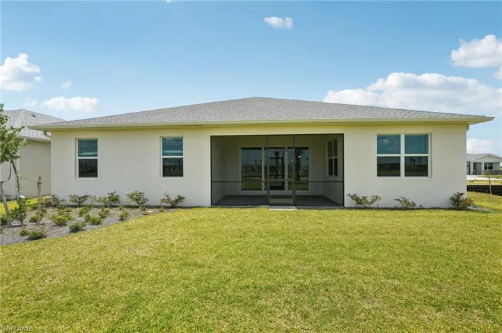 Back of house featuring stucco siding, a lawn, and a sunroom