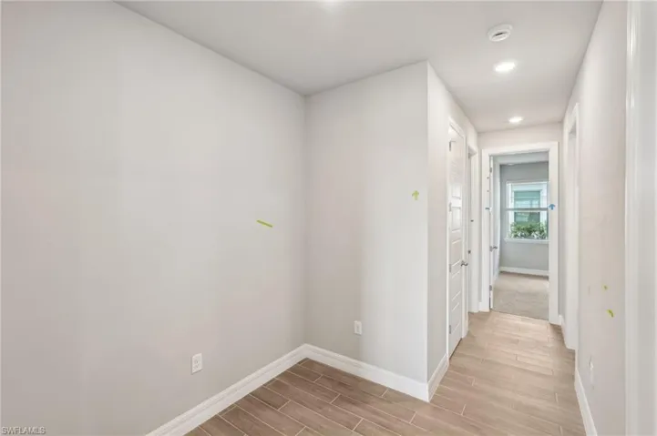 Hallway with baseboards, light wood-type flooring, and recessed lighting