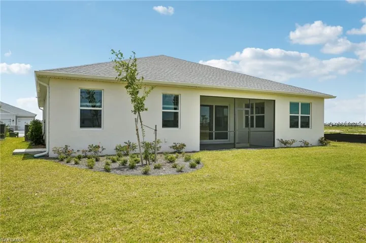 Back of house featuring a yard and stucco siding