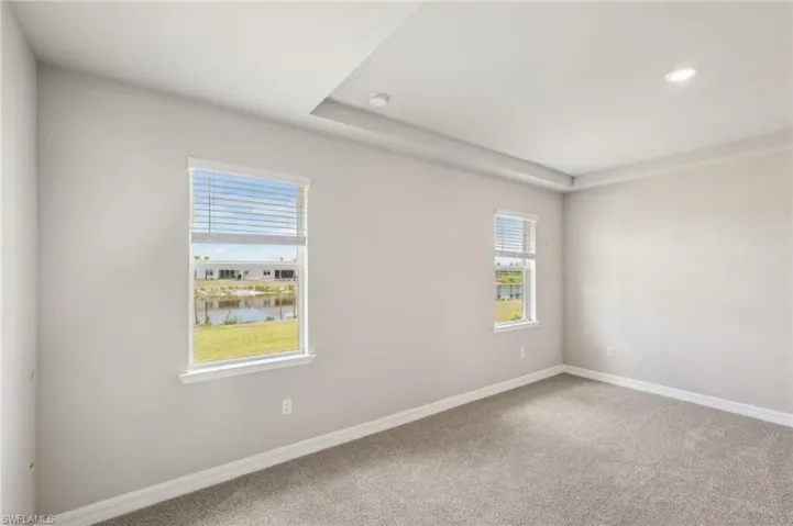 Spare room featuring carpet, baseboards, a water view, recessed lighting, and a smoke detector