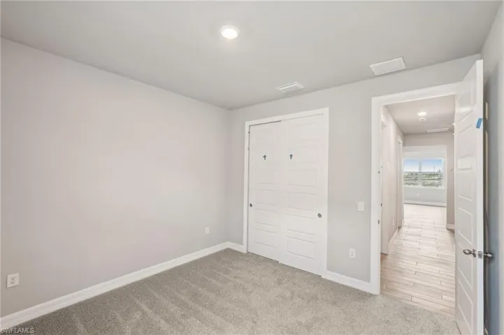 Unfurnished bedroom featuring baseboards, carpet floors, recessed lighting, and a closet