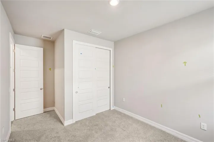 Unfurnished bedroom with light carpet, baseboards, and a closet