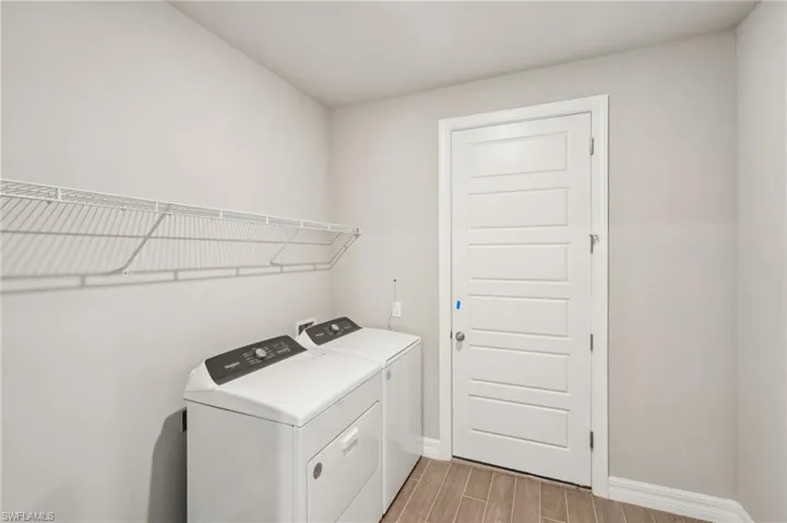 Laundry room featuring washer and clothes dryer, light wood-type flooring, and baseboards