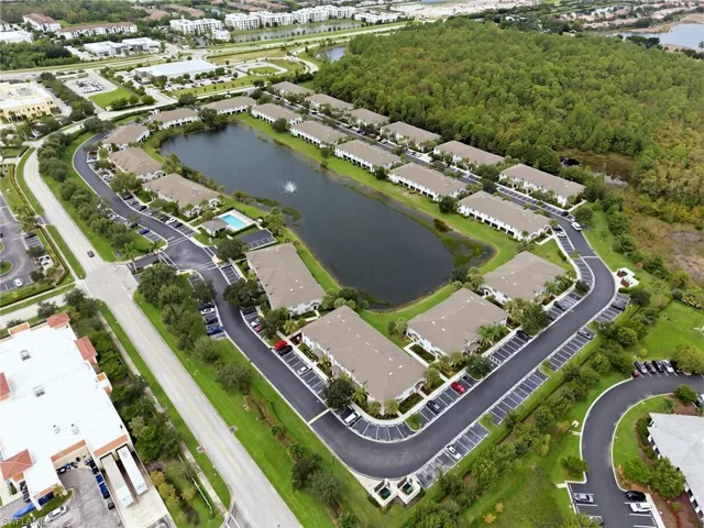 Community featuring a central pond with fountain, mature landscaping, and an outdoor swimming pool