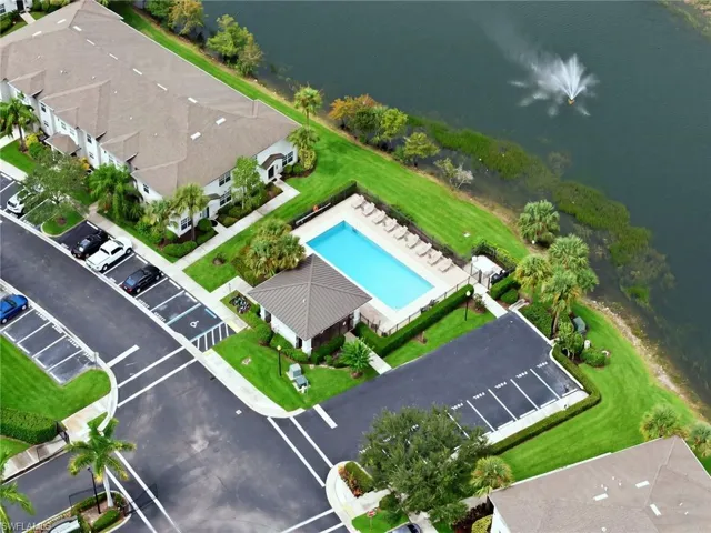 Community swimming pool with surrounding lounge chairs, lakeside setting, and well-maintained green spaces