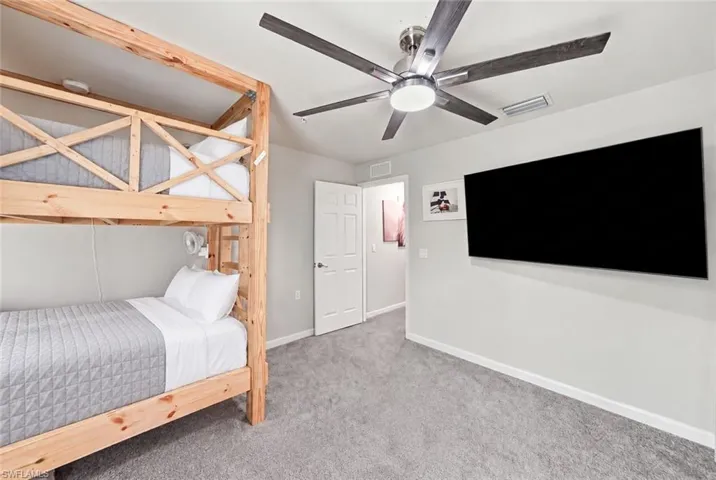 Neutral wall paint, plush carpet flooring, and a ceiling fan with integrated lighting