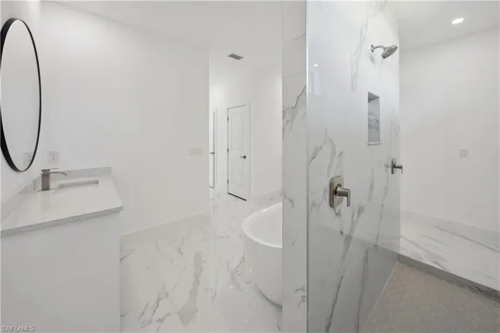 Full bathroom with a freestanding tub, a marble finish shower, light marble finish floors, vanity, and recessed lighting