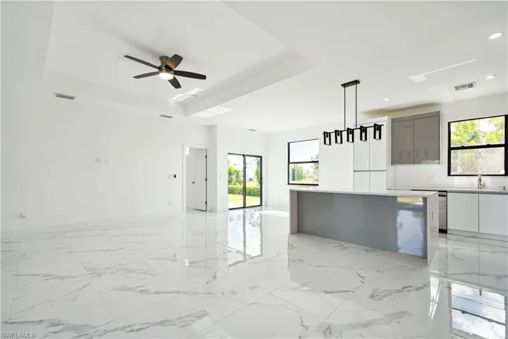 Kitchen featuring gray cabinetry, modern cabinets, a center island, light marble finish floors, and decorative light fixtures