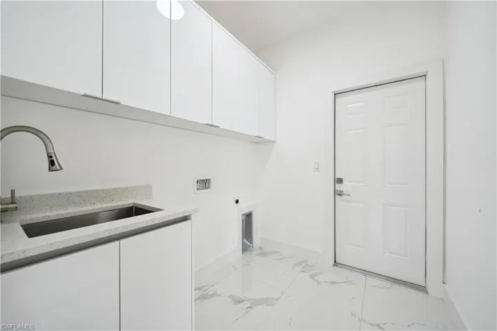 Laundry area with light marble finish floors, cabinet space, hookup for an electric dryer, and hookup for a washing machine