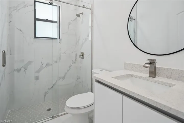 Bathroom with vanity and a marble finish shower