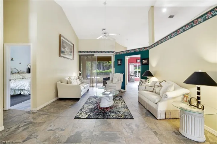 Living area with a ceiling fan, baseboards, high vaulted ceiling, and stone finish flooring
