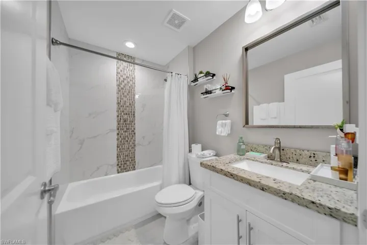 Full bathroom featuring a white vanity with a light-colored speckled countertop, an undermount sink, and a brushed nickel faucet