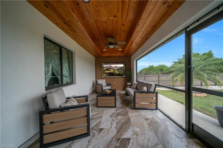 Expansive screened patio featuring wood-finish plank ceiling, recessed lighting, ceiling fan, and large format floor tile