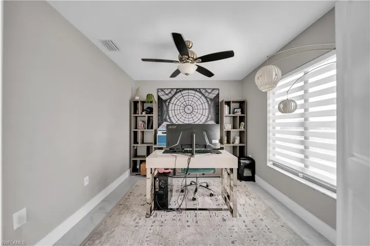 Neutral-toned room featuring a ceiling fan, a window with horizontal blinds, and a decorative light fixture