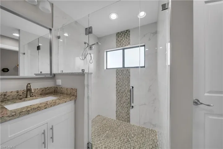 Glass-enclosed shower with mosaic tile floor, white subway tile walls, and a recessed window