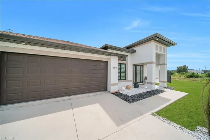 Modern exterior featuring a prominent two-car garage, white stucco finish, and a covered entry with columns