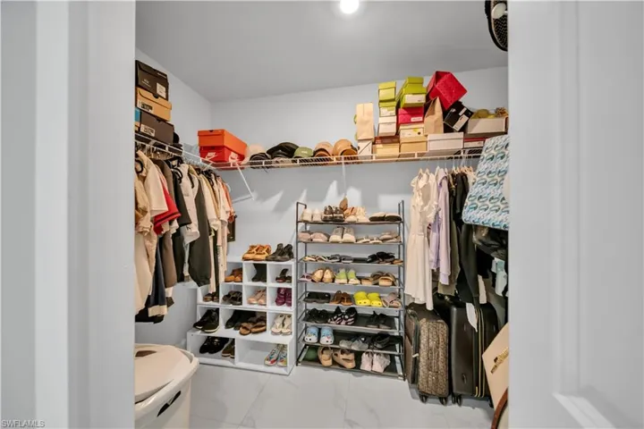 Walk-in closet with white walls and light-colored flooring