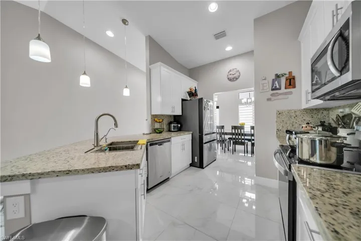 Kitchen featuring white cabinetry, granite countertops, stainless steel appliances, and tile flooring